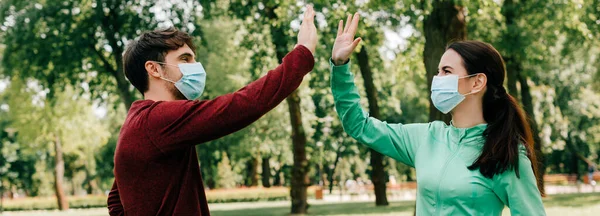 Horizontal image of sportsman in medical mask high five to girlfriend in park — Stock Photo