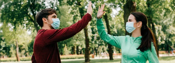 Imagen horizontal del deportista en máscara médica de cinco a novia en el parque - foto de stock