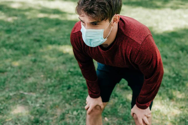 Jovem desportista em máscara médica em pé no parque — Fotografia de Stock