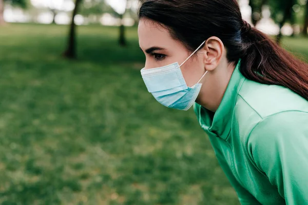 Seitenansicht einer Sportlerin mit medizinischer Maske, die im Park wegschaut — Stockfoto