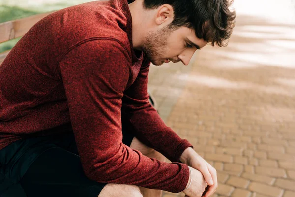 Side view of handsome sportsman resting on bench in park — Stock Photo