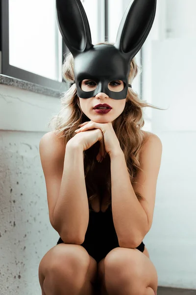 Young woman in rabbit mask looking at camera near window — Stock Photo