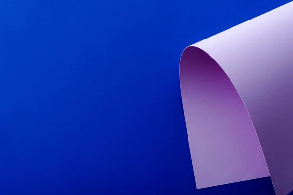 Violeta colorido papel remolino sobre fondo azul - foto de stock