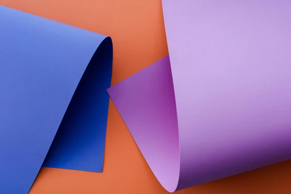 Papier coloré bleu et violet sur fond orange — Photo de stock