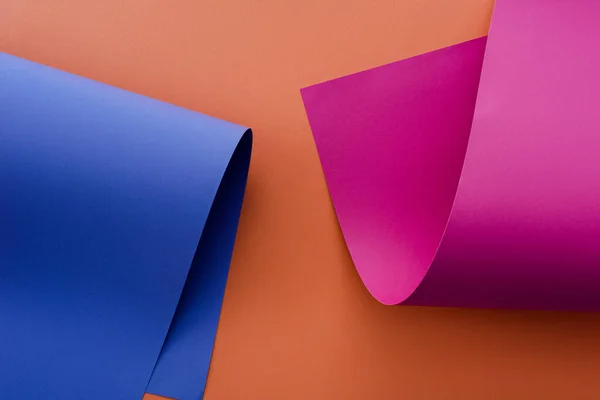 Papel colorido azul y rosa sobre fondo naranja - foto de stock
