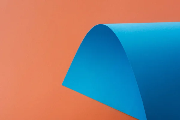 Blue colorful paper swirl on orange background — Stock Photo