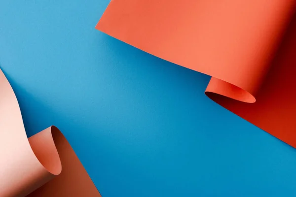 Naranja colorido papel remolinos sobre fondo azul - foto de stock
