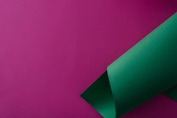 Papier coloré vert tourbillonnant sur fond violet — Photo de stock