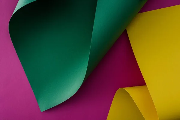 Redemoinhos de papel coloridos verdes e amarelos em fundo roxo — Fotografia de Stock