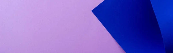 Gebogenes blaues Papier auf violettem Hintergrund, Panoramaaufnahme — Stockfoto