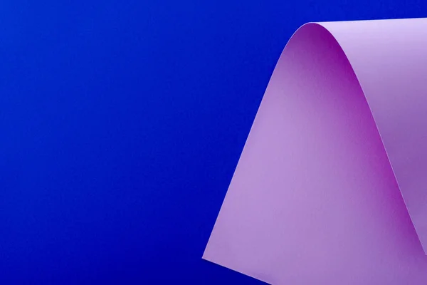 Curved lilac paper on blue background — Stock Photo