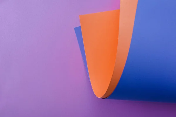 Papel laranja e azul sobre fundo violeta — Fotografia de Stock