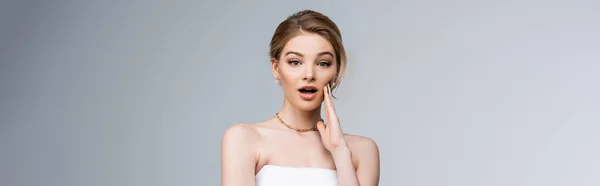 Panoramic shot of shocked bride looking at camera isolated on grey — Stock Photo