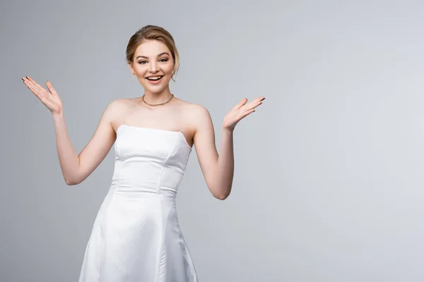 Sposa allegra in abito da sposa bianco gesticolando isolato sul grigio — Foto stock