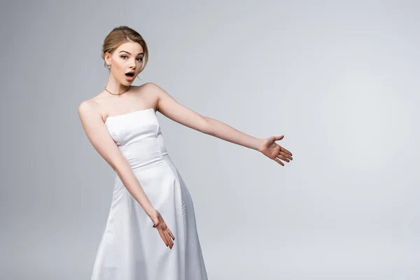 Surprised bride in white wedding dress gesturing isolated on grey — Stock Photo