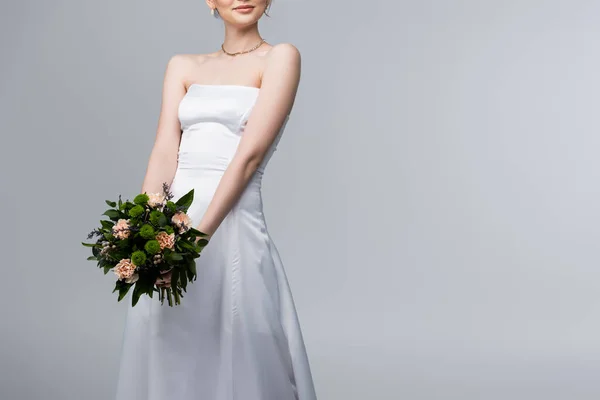 Vista ritagliata della sposa in abito da sposa bianco con fiori isolati su grigio — Foto stock