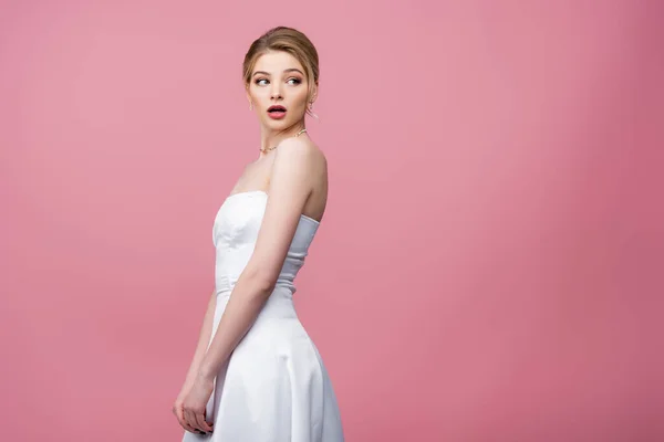 Surprised bride in white wedding dress looking away isolated on pink — Stock Photo