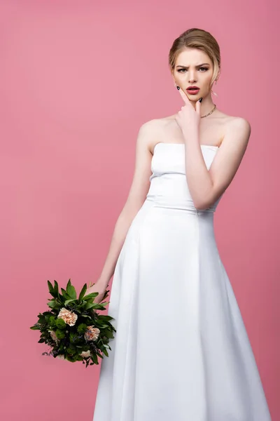 Novia reflexiva en vestido de novia blanco con flores aisladas en rosa - foto de stock