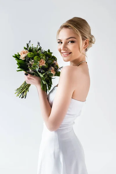 Happy bride in elegant wedding dress holding flowers isolated on white — Stock Photo
