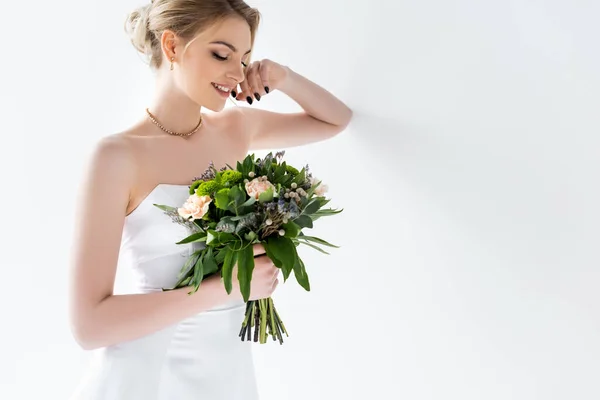 Happy young bride in elegant wedding dress holding flowers on white — Stock Photo