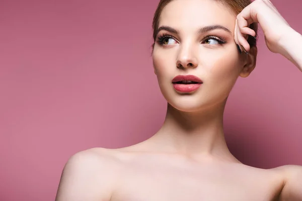 Mujer desnuda y joven con maquillaje mirando hacia otro lado en rosa - foto de stock