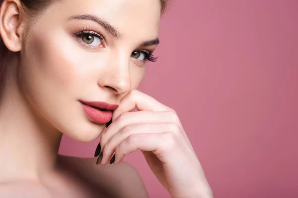 Nude and pretty woman with makeup looking at camera and touching face isolated on pink — Stock Photo