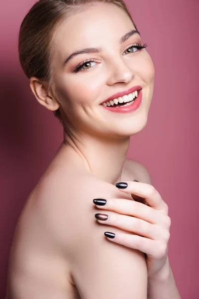 Nude and happy woman with makeup looking at camera while smiling on pink — Stock Photo