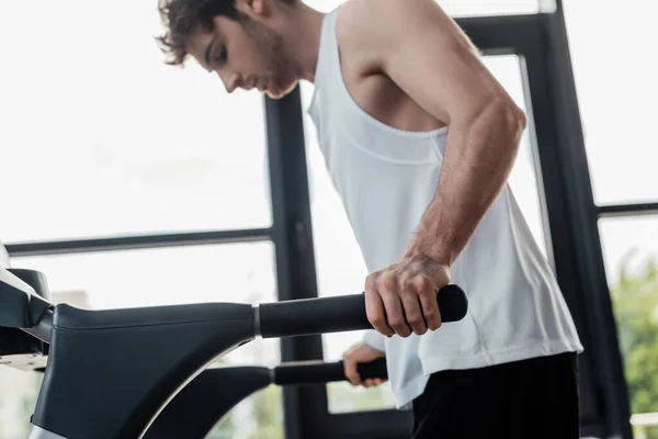 Selective focus of tired sportsman touching handrails on treadmill — Stock Photo