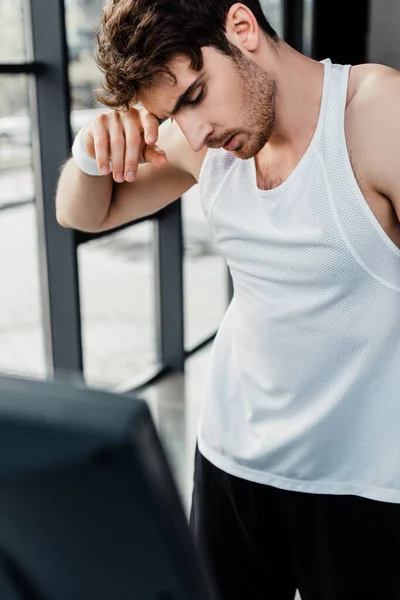Selective focus of tired sportsman touching face in gym — Stock Photo