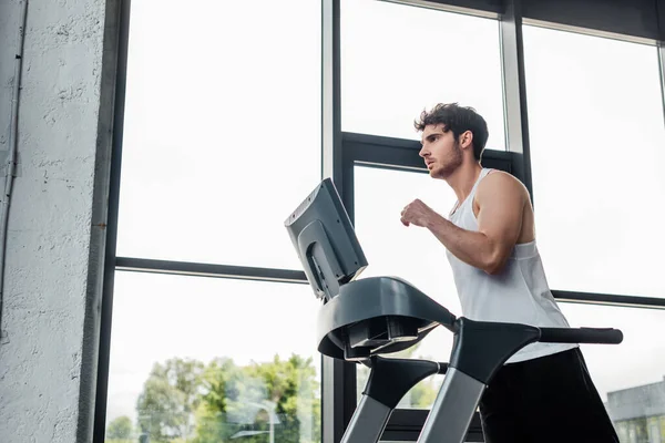 Handsome man in sportswear running on treadmill — Stock Photo
