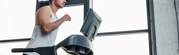 Panoramic crop of man in sportswear running on treadmill — Stock Photo