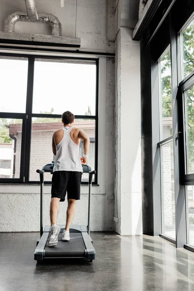 Visão traseira do desportista correndo em esteira na academia — Fotografia de Stock