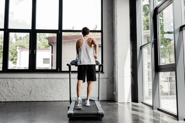 Back view of man running on treadmill in gym — Stock Photo
