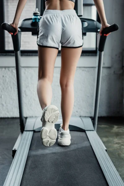 Back view of sportswoman running on treadmill in gym — Stock Photo