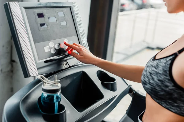 Cropped view of sportswoman pointing with finger at screen on modern treadmill — Stock Photo