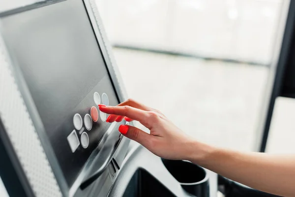 Cropped view of woman pointing with finger at screen on modern treadmill — Stock Photo