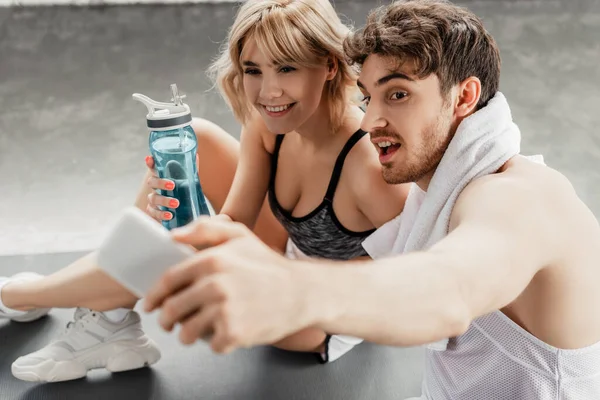 Enfoque selectivo de la pareja deportiva tomando selfie en el gimnasio - foto de stock