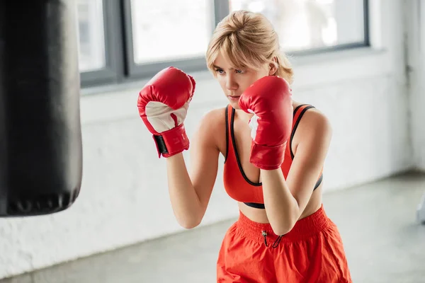 Foyer sélectif de la fille sportive dans des gants de boxe exercice avec sac de boxe — Photo de stock