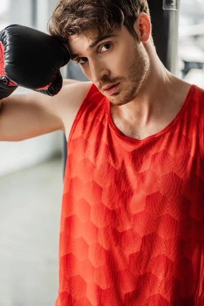 Hombre cansado en ropa deportiva y guante de boxeo tocando la cara - foto de stock