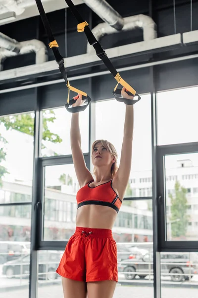 Athletic girl in sportswear working out with resistance bands in gym — Stock Photo