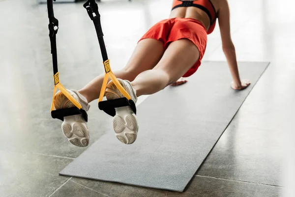 Cropped view of woman in sportswear doing plank while exercising with resistance bands — Stock Photo