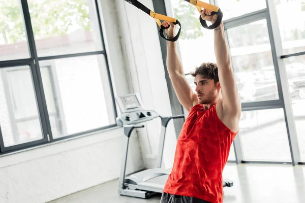 Schöner und athletischer Sportler, der im Fitnessstudio mit Gummibändern trainiert — Stockfoto