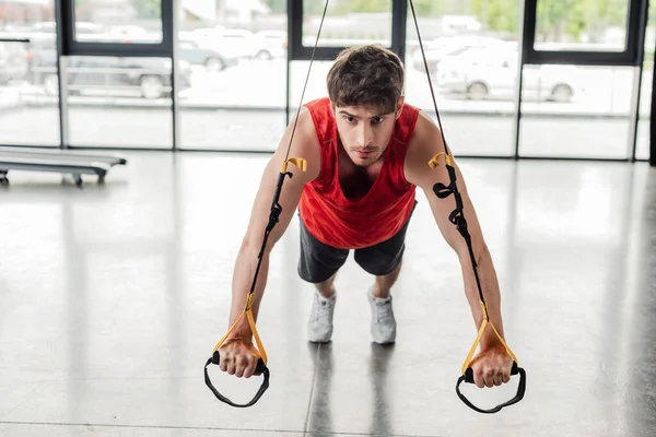 Handsome and athletic man working out with elastics in gym — Stock Photo