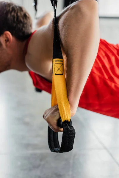 Vista recortada de un hombre fuerte haciendo ejercicio con elásticos en el gimnasio - foto de stock