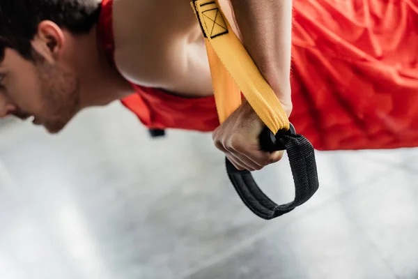 Visão cortada do homem esportivo trabalhando com elásticos no ginásio — Fotografia de Stock