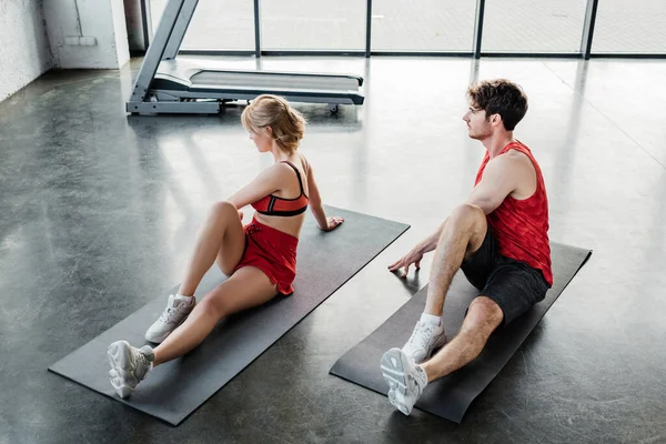 Deporte pareja en ropa deportiva estiramiento en colchonetas de fitness en el gimnasio - foto de stock