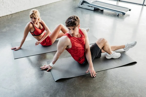 Sportive couple in sportswear stretching on fitness mats in gym — Stock Photo