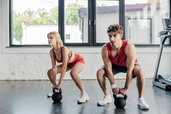 Deporte pareja haciendo ejercicio con pesadas mancuernas en el gimnasio — Stock Photo