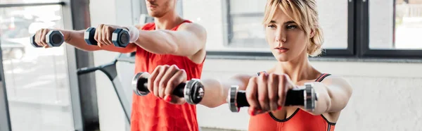 Panoramic orientation of sport couple exercising with dumbbells in gym — Stock Photo