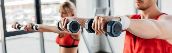 Panoramic concept of sport couple exercising with dumbbells in gym — Stock Photo